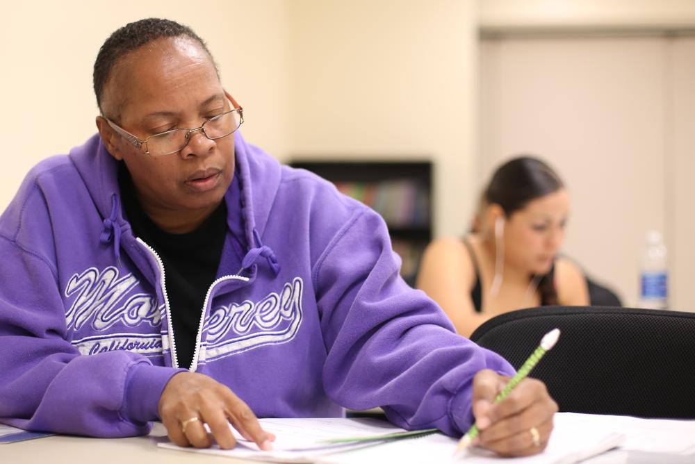 A man wearing a purple hoodie taking notes in class